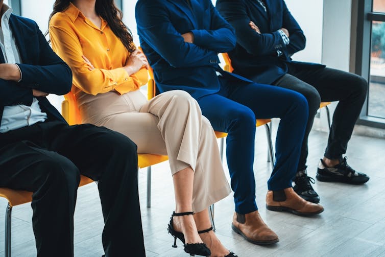 men and woman sitting in a row waiting for a job interview